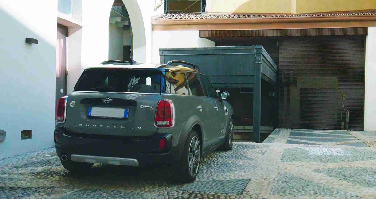 Car lift installed in a residential courtyard with a Mini Cooper