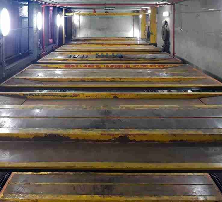 Automatic parking interior before renovation - rusty yellow and red platforms, dirty walls, poor lighting